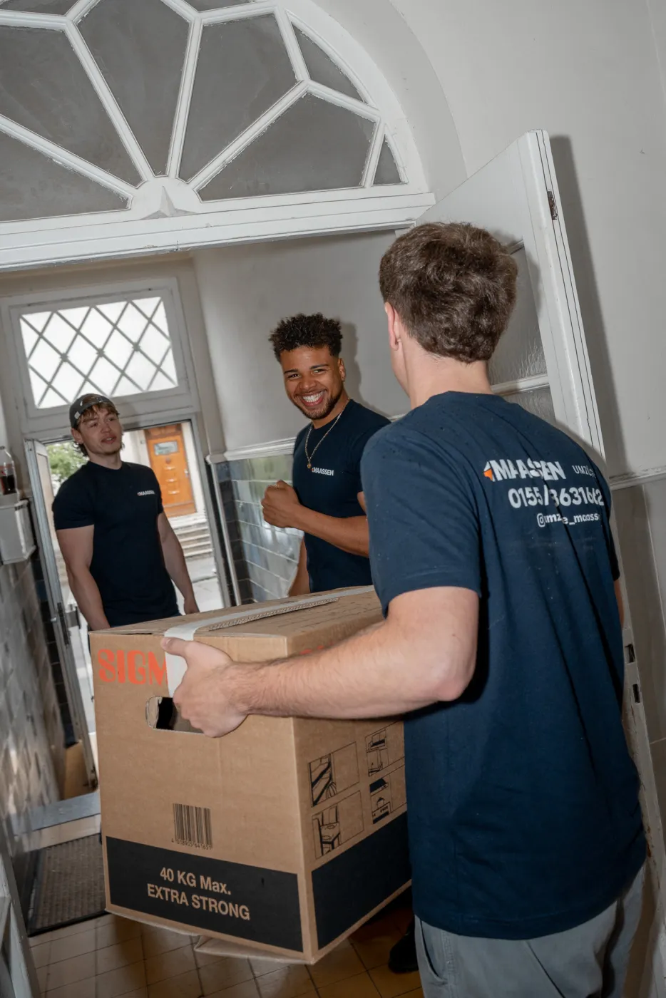 Maassen Umzüge Team trägt Umzugskartons durch die Eingangstür in Krefeld