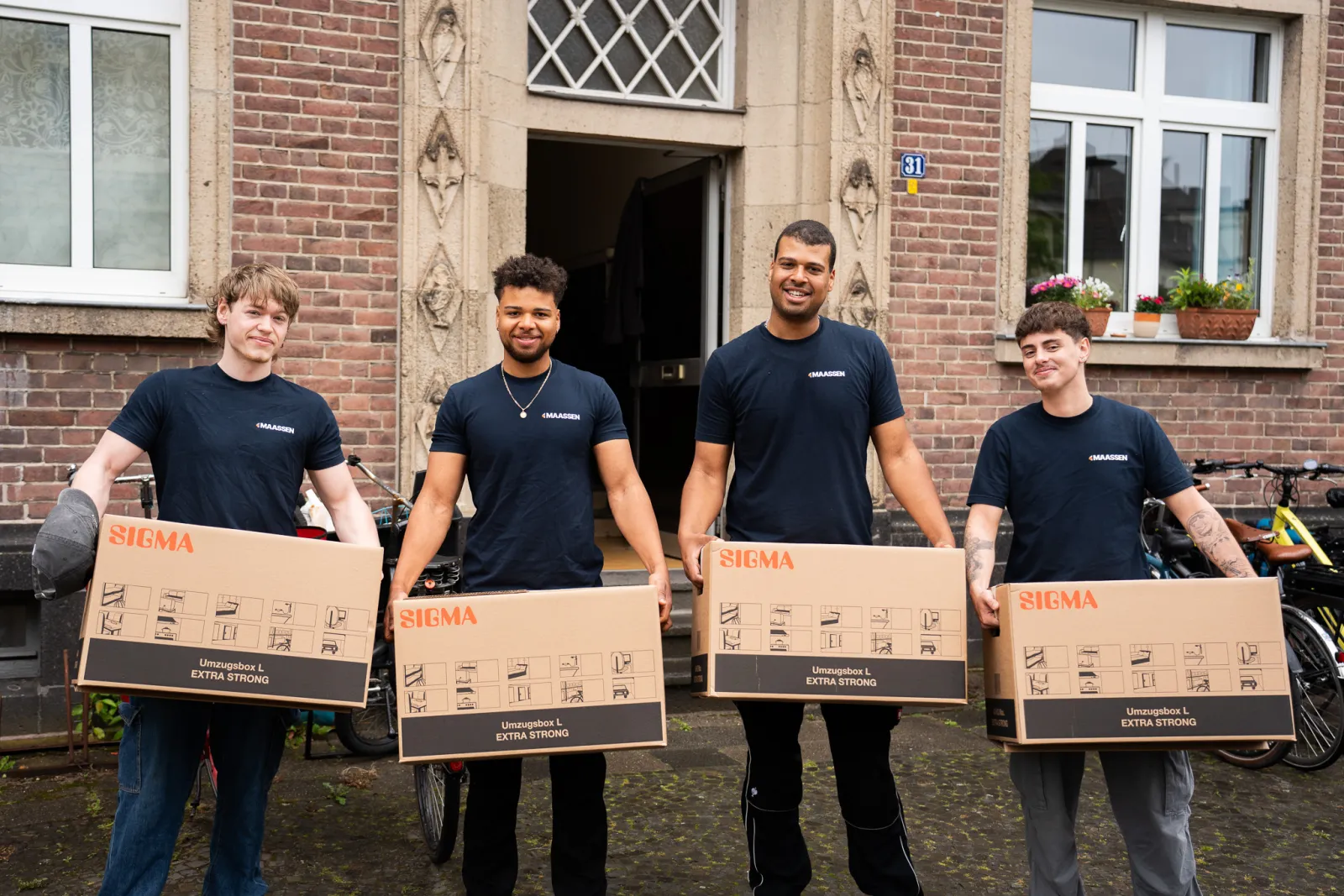 Das Team von Maassen Umzüge aus Krefeld mit Umzugskartons vor einem Haus